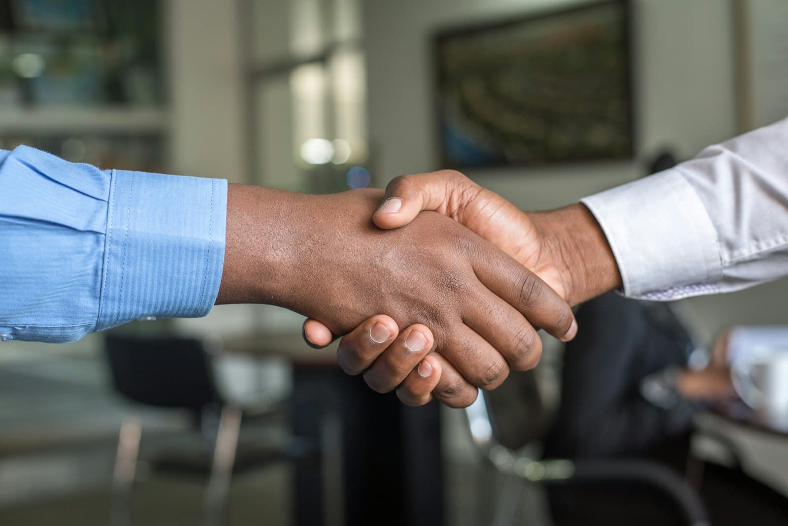 Two professionals shaking hands over a signed agreement